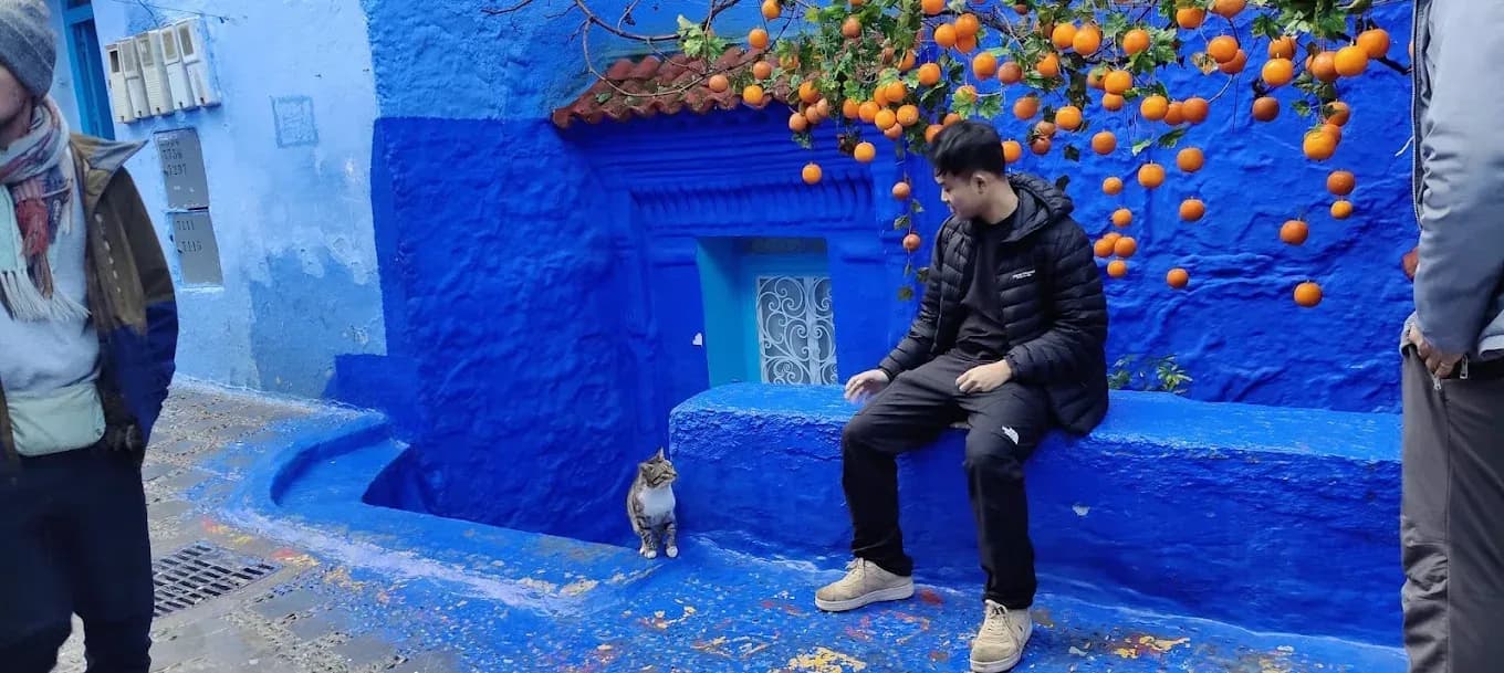 Viajero sentado junto a una pared azul de Chefchaouen