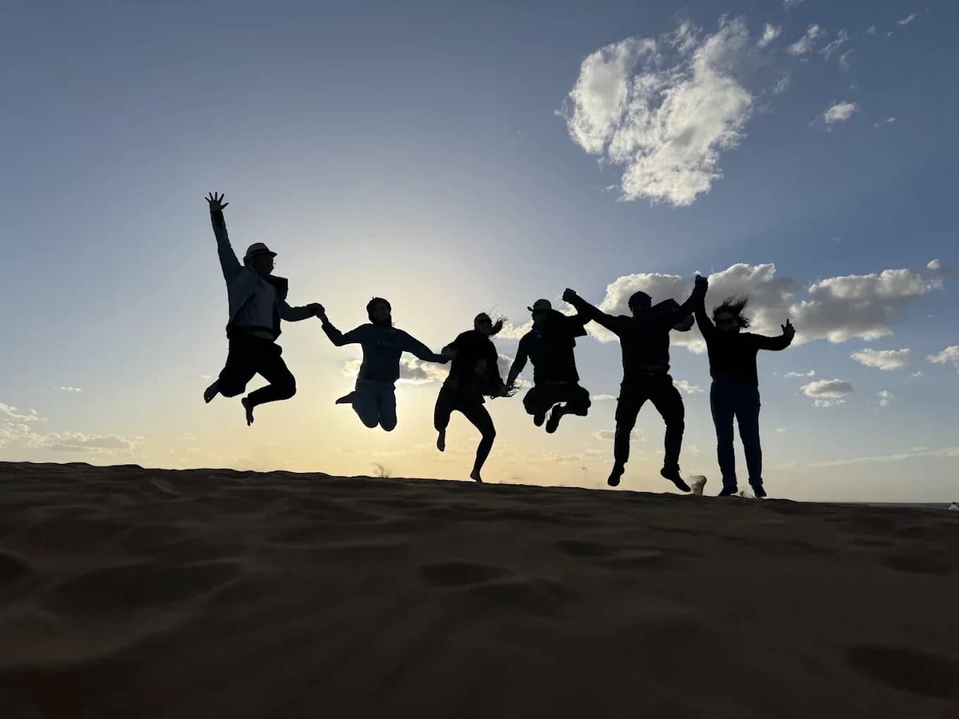 Grupo saltando en las dunas al atardecer