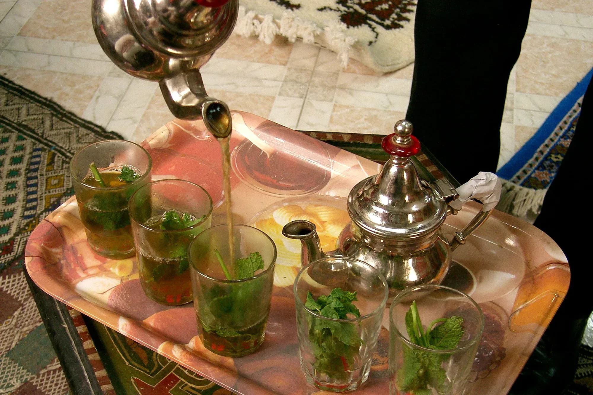 Té a la menta servido desde la tetera en vasos sobre una bandeja, en Tánger