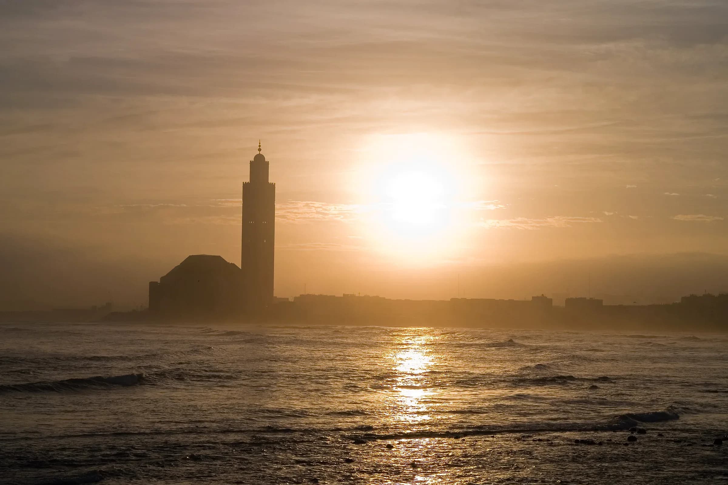 Mezquita Hassan II de Casablanca al atardecer, con el sol sobre el océano Atlántico