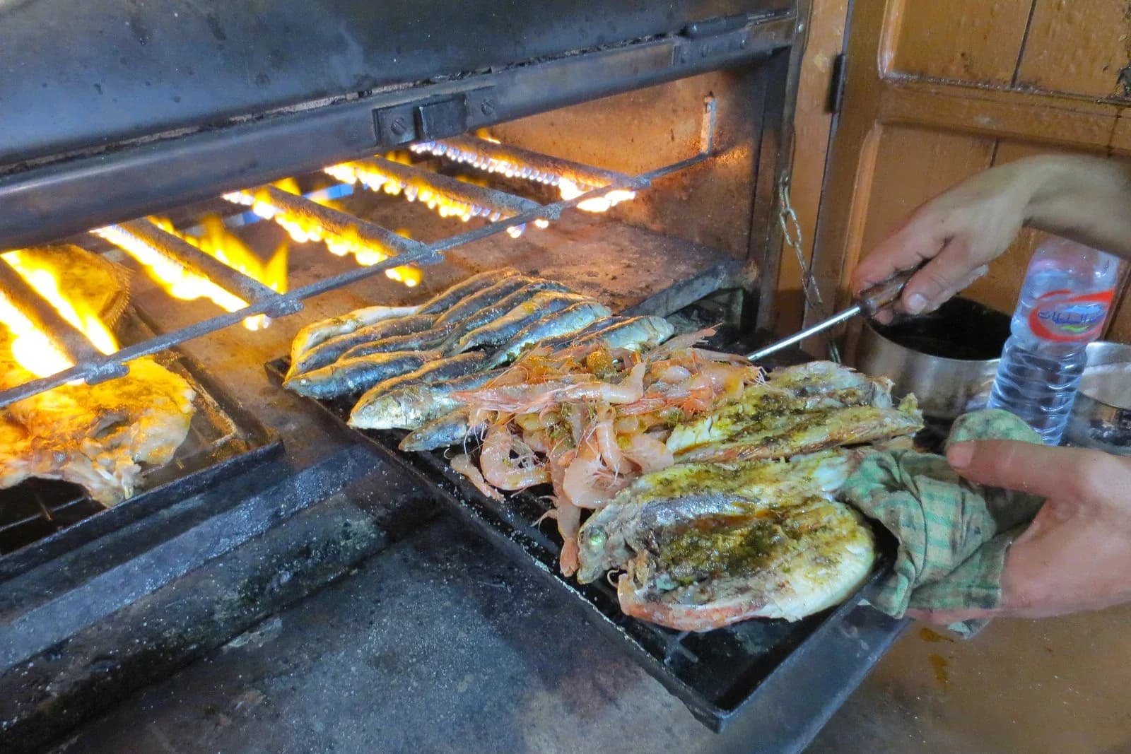 Sardinas, gambas y pescado asándose en una parrilla en Essaouira