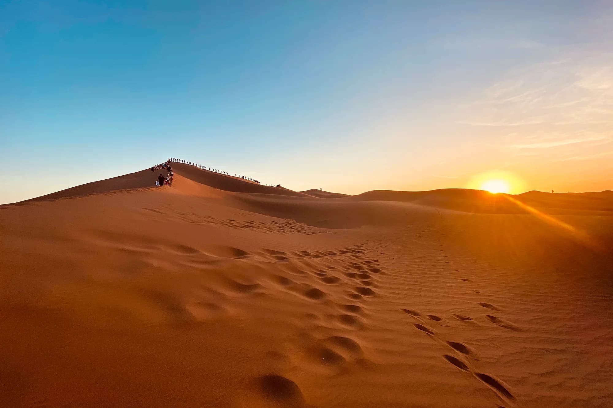 Sol bajo sobre las dunas de Zagora, con huellas en la arena