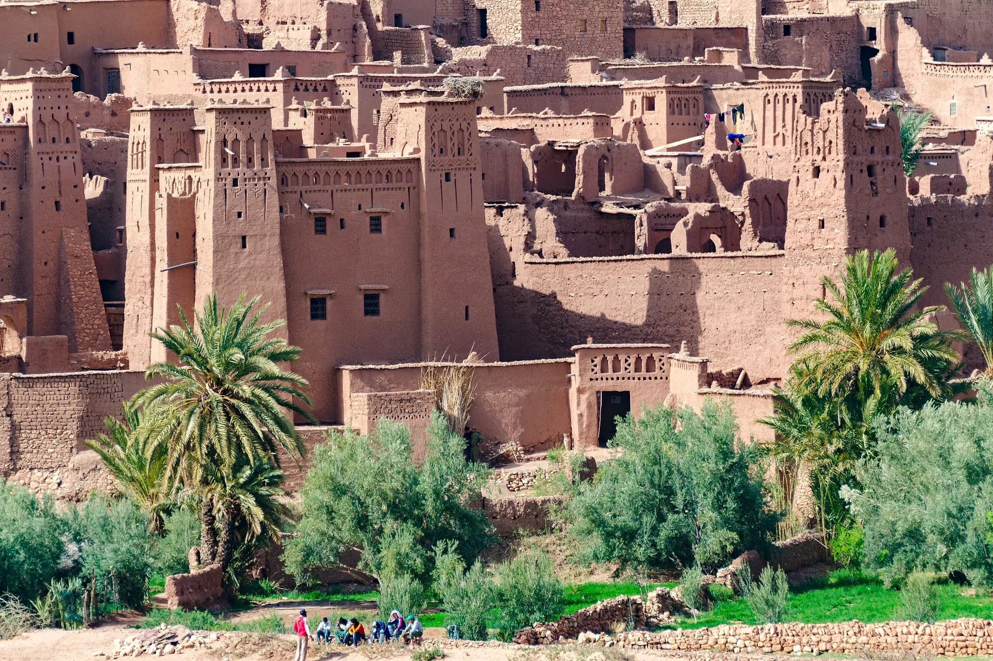 Casas y torres de adobe del ksar de Aït Ben Haddou entre palmeras junto al río