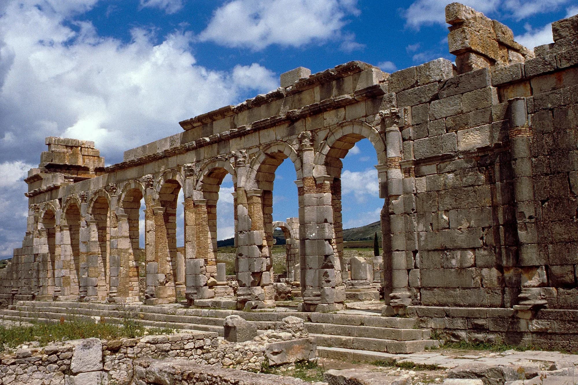 Arcadas de la basílica romana de Volubilis bajo un cielo con nubes