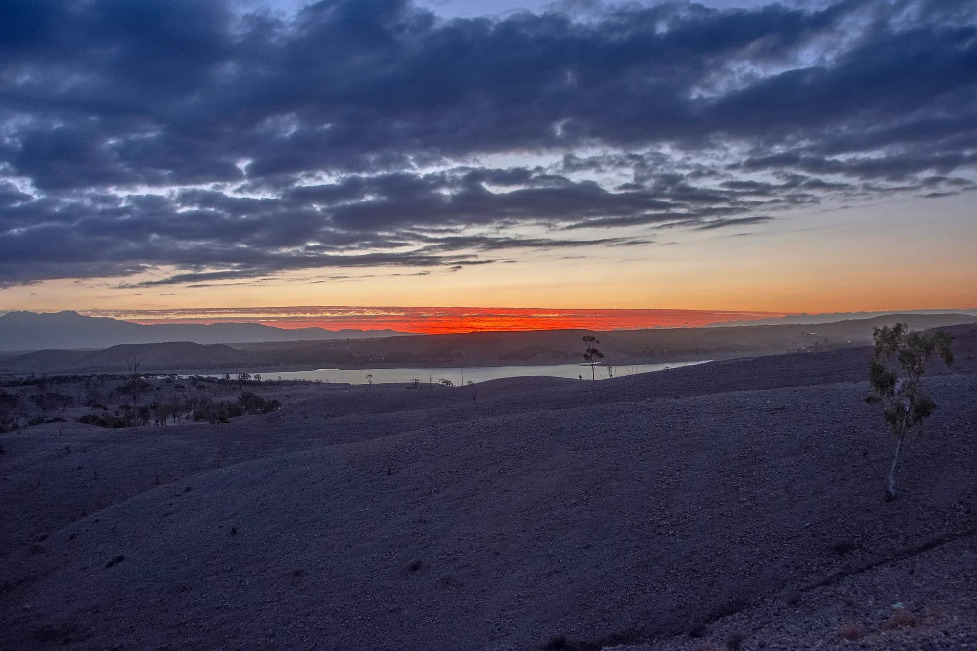 Puesta de sol con nubes sobre las colinas del desierto de Agafay, cerca de Marrakech