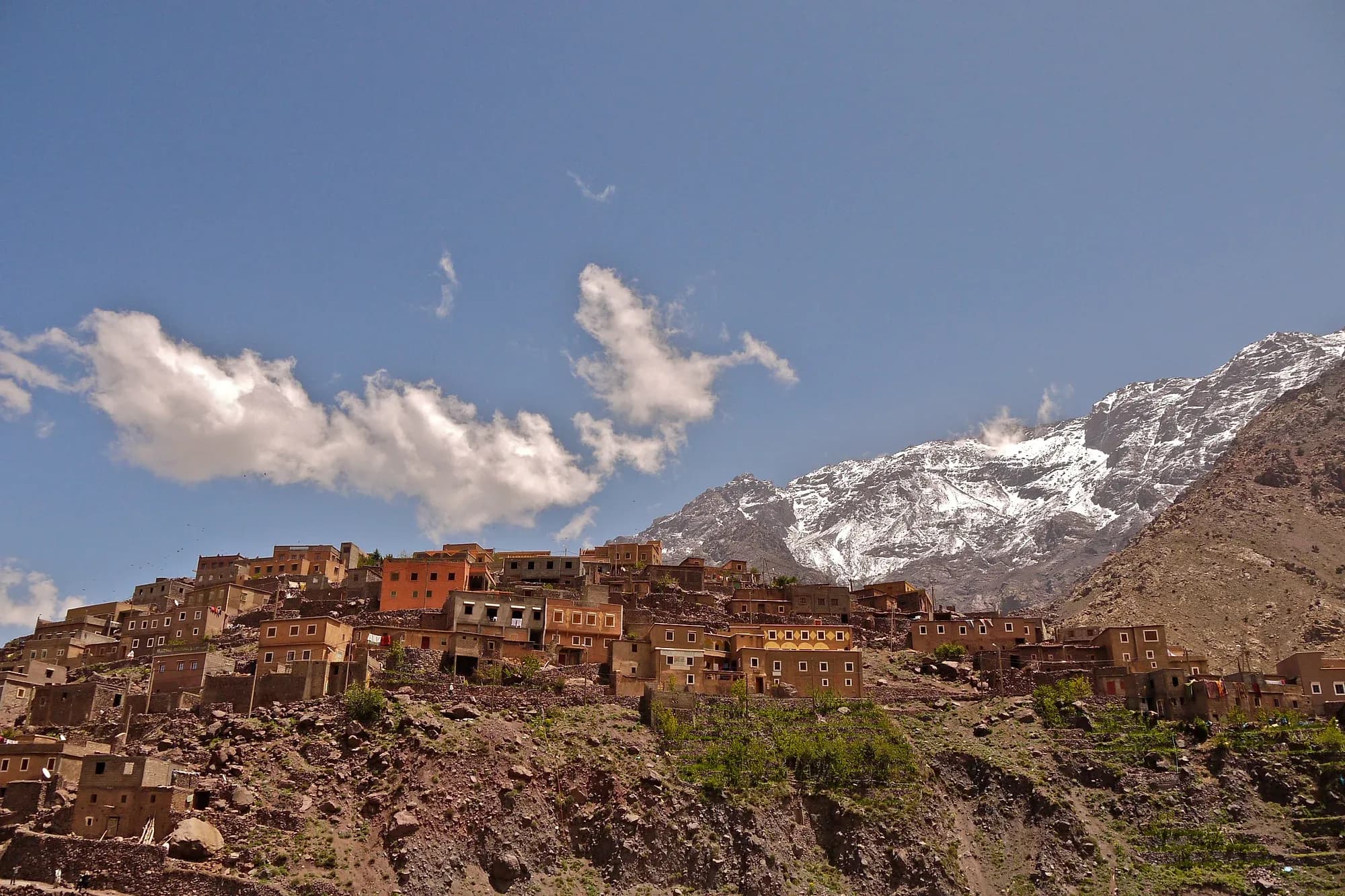 Pueblo bereber de Aroumd sobre una ladera rocosa con cumbres nevadas del Alto Atlas al fondo