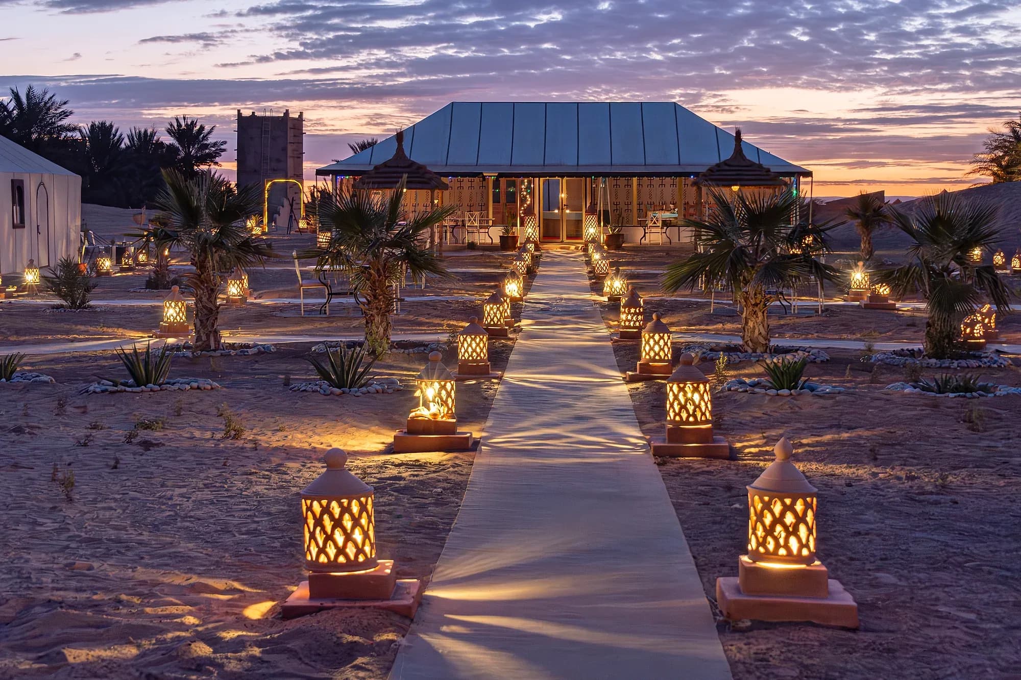 Campamento de lujo iluminado con faroles al anochecer en Erg Chebbi