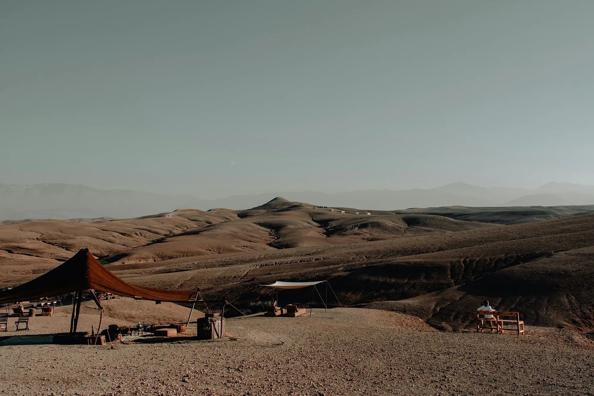 Jaimas y zona de descanso de un campamento entre las colinas pedregosas del desierto de Agafay