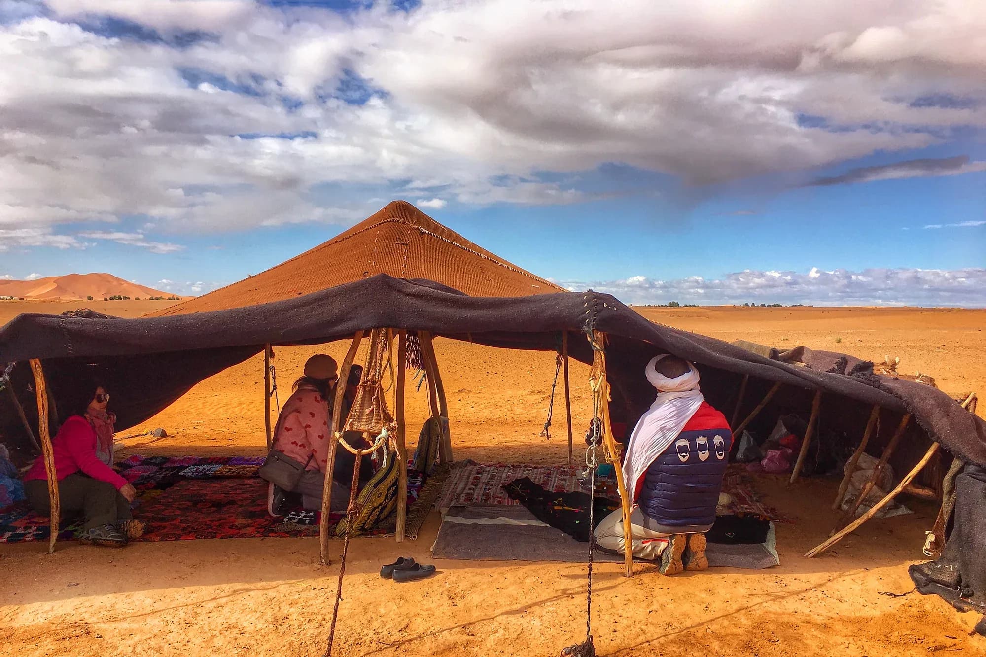 Jaima bereber abierta con alfombras frente a una duna de Erg Chebbi