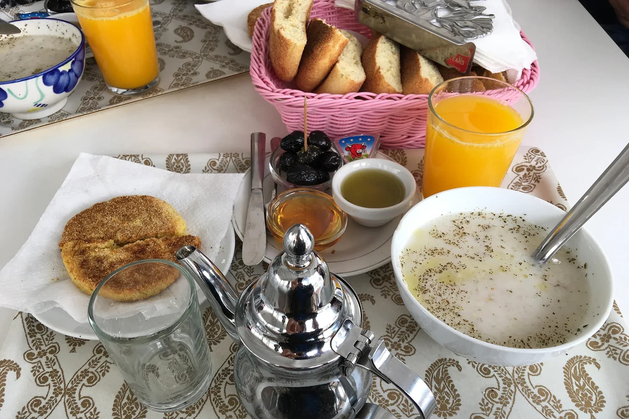 Moroccan breakfast with mint tea, harcha, olives, honey, oil, orange juice and soup